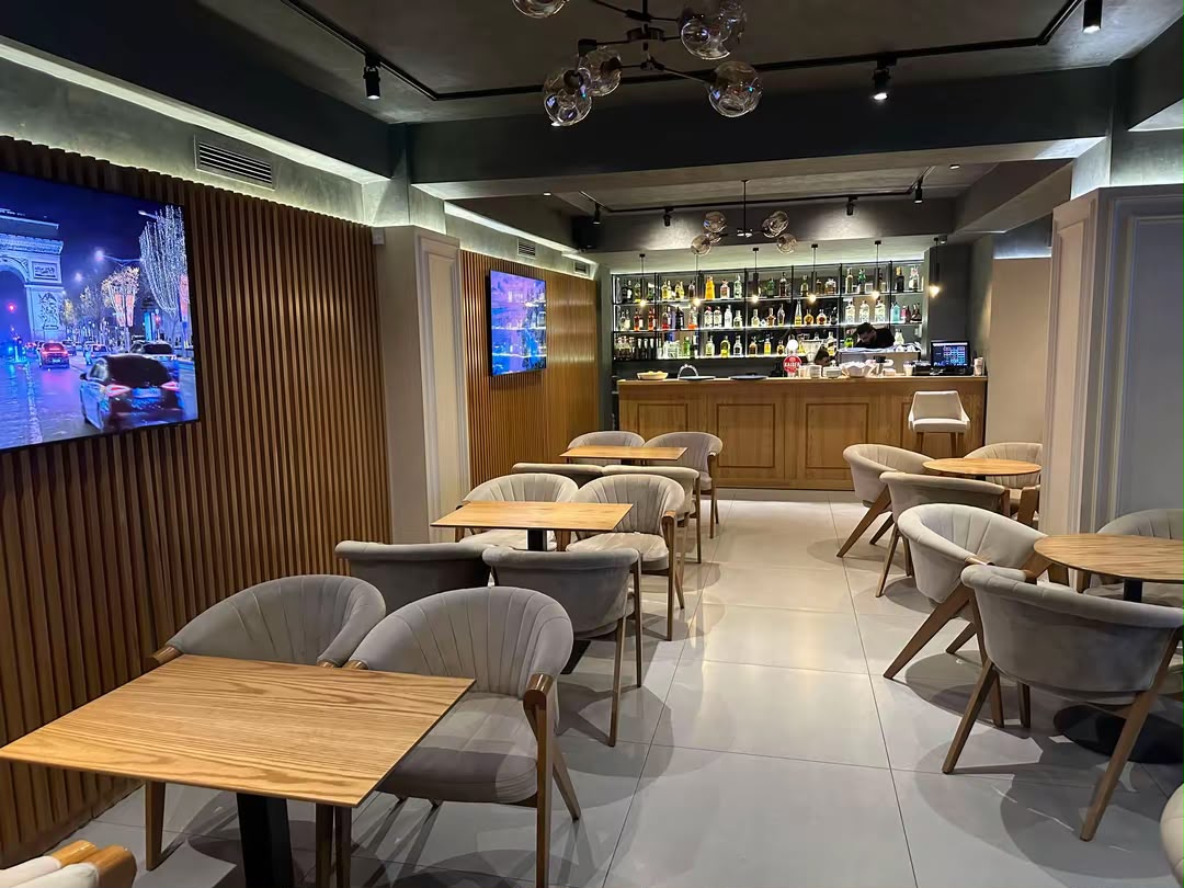 Lounge seating with velvet chairs, wood panelling and screens showing sport